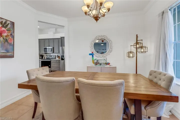 Dining space with an inviting chandelier, baseboards, crown molding, and light tile patterned flooring