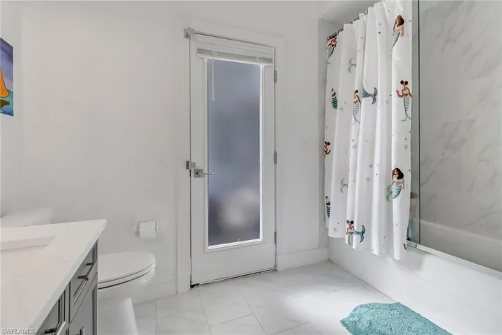 Bathroom with vanity, marble finish floor, toilet, and shower / tub combo