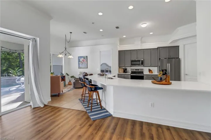 Kitchen featuring light countertops, gray cabinetry, ornamental molding, a breakfast bar, and stainless steel appliances