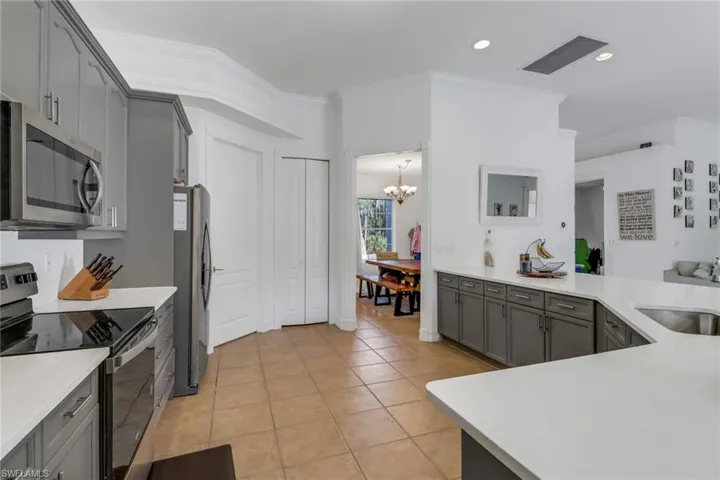 Kitchen with an inviting chandelier, ornamental molding, gray cabinets, a sink, and stainless steel appliances