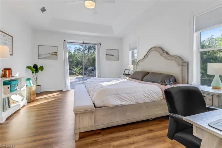 Bedroom with access to outside, a tray ceiling, visible vents, and multiple windows