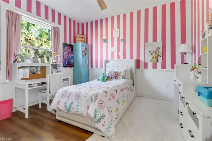 Bedroom with ceiling fan, wood finished floors, and wallpapered walls