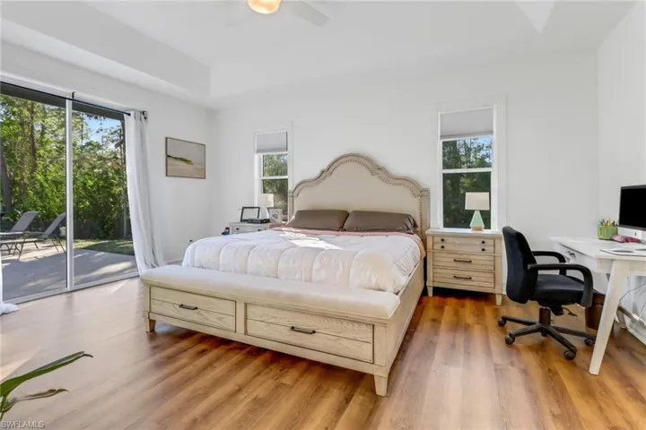 Bedroom featuring a raised ceiling, access to outside, a ceiling fan, and light wood-style flooring