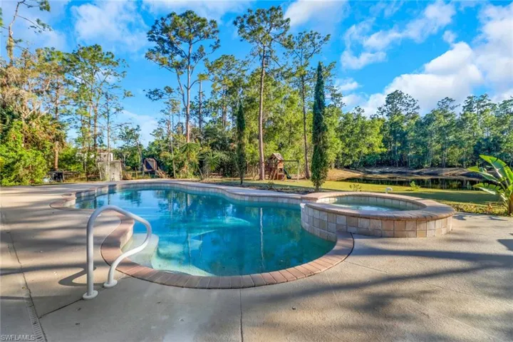 View of swimming pool featuring a playground and a pool with connected hot tub