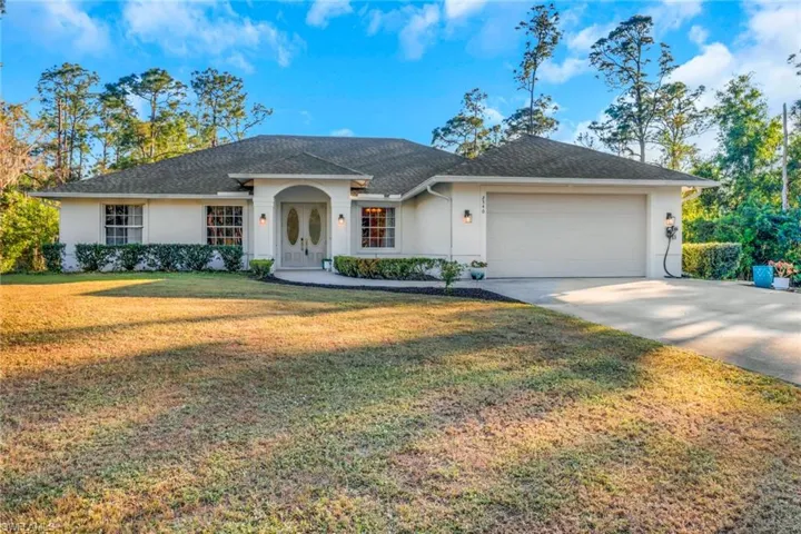 Single story home featuring a garage, driveway, a front yard, and stucco siding
