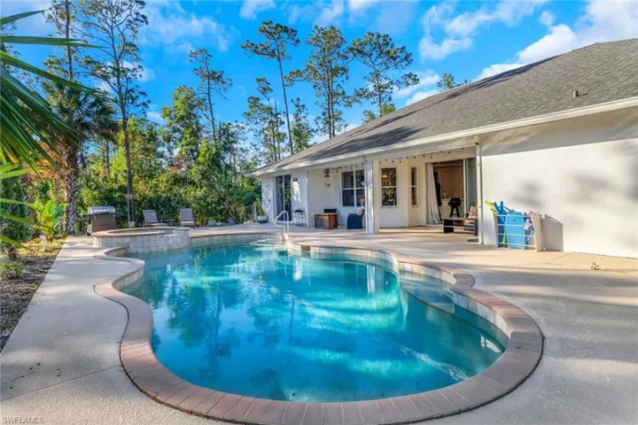 View of pool featuring a pool with connected hot tub, a patio area, and a grill