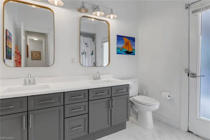 Full bath featuring double vanity, toilet, a sink, and marble finish floor