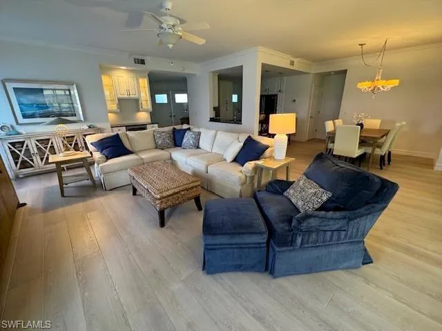 Living area featuring ornamental molding, light wood finished floors, and a ceiling fan