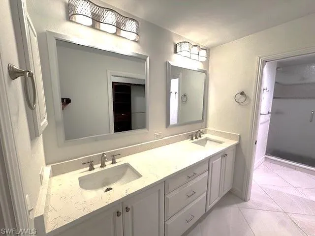 Full bath featuring double vanity and light tile patterned floors