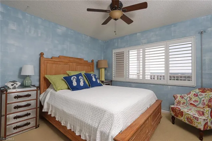 Bedroom with light carpet, ceiling fan, and a textured ceiling