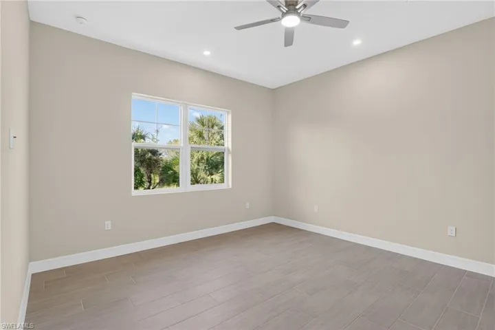 Empty room featuring ceiling fan, wood tiled floors, and recessed lighting