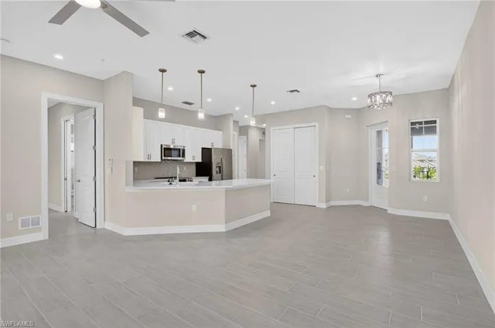 Kitchen with white cabinets, stainless steel appliances, open floor plan, ceiling fan, and a peninsula