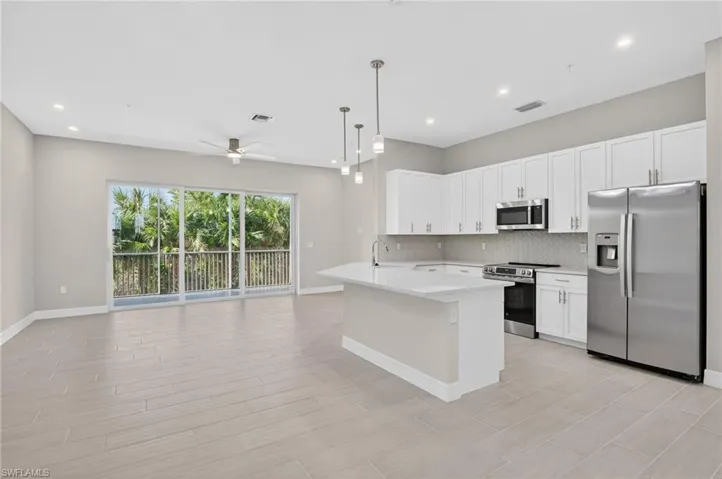 Kitchen with stainless steel appliances, light countertops, pendant lighting, and white cabinets