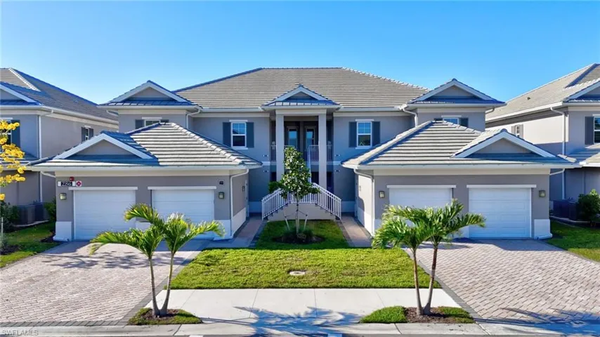Traditional home featuring a tiled roof, stucco siding, a front lawn, driveway, and a garage