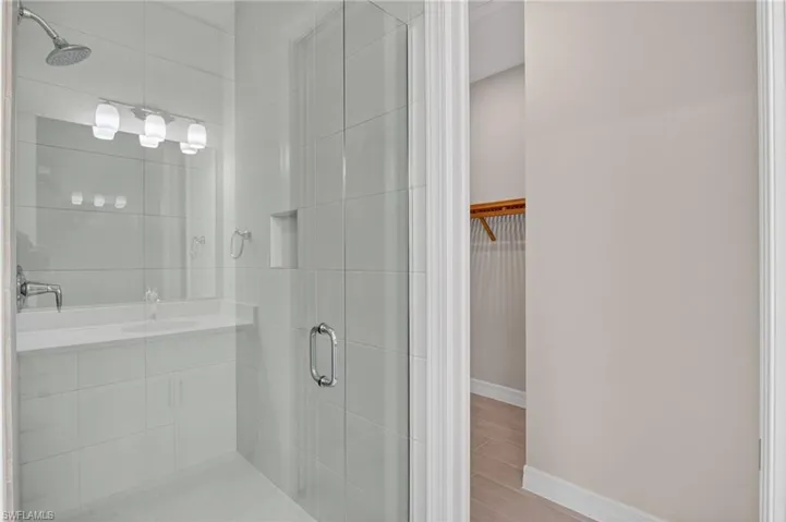 Bathroom featuring a walk in closet, vanity, a shower stall, and light wood finished floors