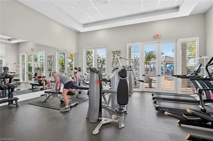 Gym featuring french doors and a raised ceiling