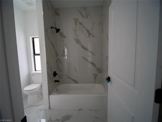 Full bathroom with a combined bath / shower with marble appearance and marble finish flooring
