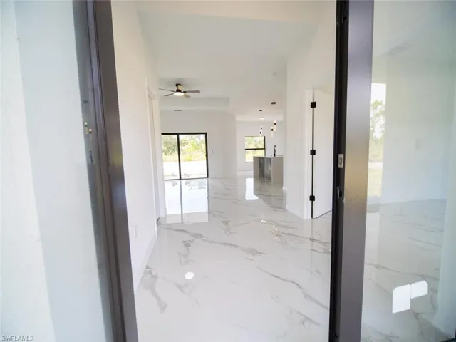 Corridor featuring light marble finish floors and baseboards