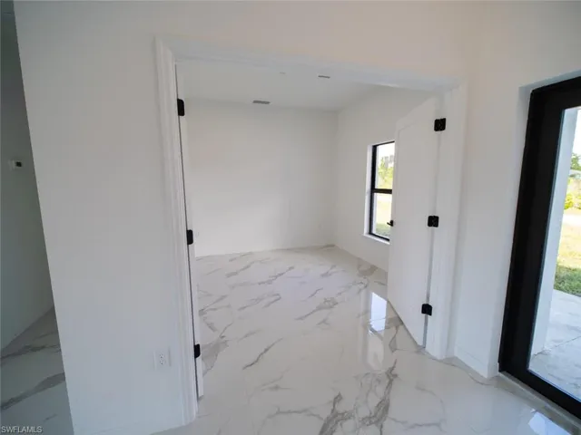 Spare room featuring light marble finish flooring and baseboards