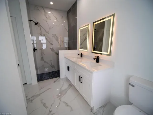Master Bathroom with a marble finish shower, double vanity, and light marble finish flooring