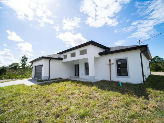 Front of property featuring driveway, stucco siding, a lawn, and a garage