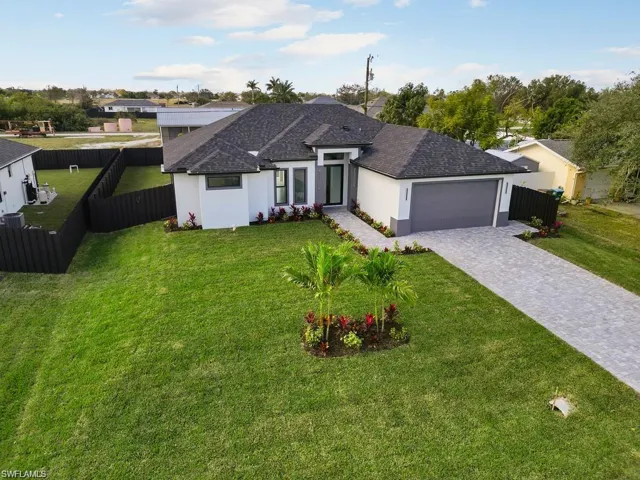 Ranch-style home with a front yard, fence, stucco siding, a garage, and decorative driveway