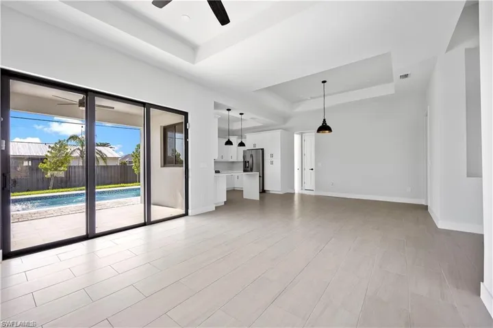 Unfurnished living room featuring a raised ceiling, visible vents, baseboards, and ceiling fan