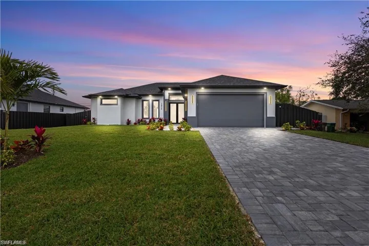 Prairie-style home with stucco siding, decorative driveway, a garage, and fence