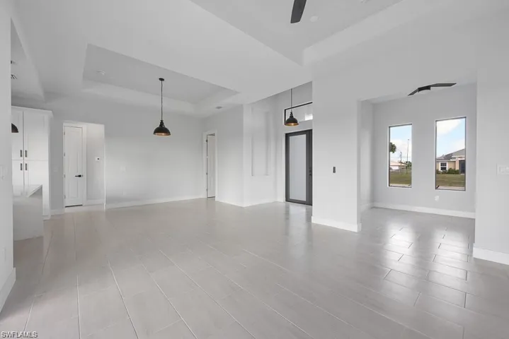 Spare room featuring a tray ceiling, baseboards, and a ceiling fan
