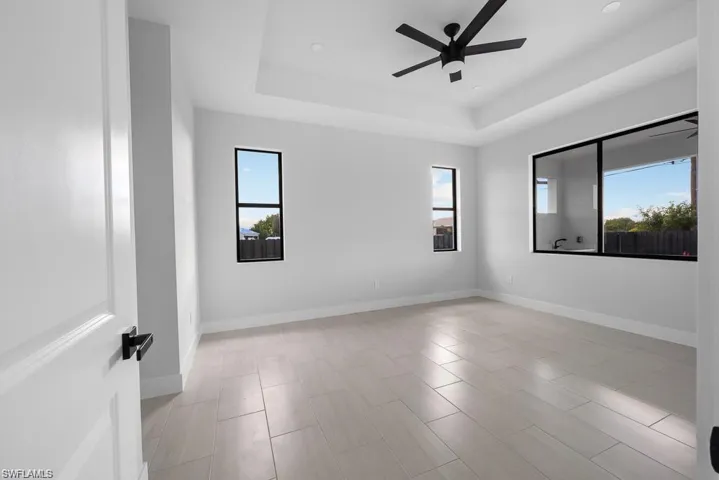 Empty room with baseboards, a ceiling fan, and a tray ceiling