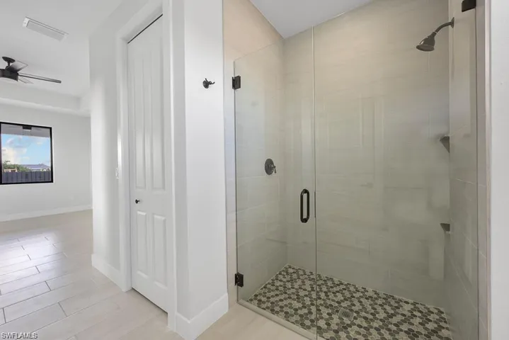 Full bathroom with a ceiling fan, visible vents, baseboards, wood finish floors, and a shower stall