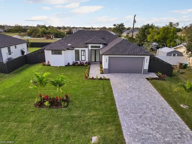View of front of property featuring stucco siding, a front lawn, decorative driveway, a shingled roof, and a garage