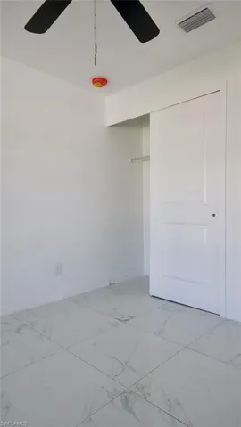 Room with large format tile flooring, white walls, and a ceiling fan