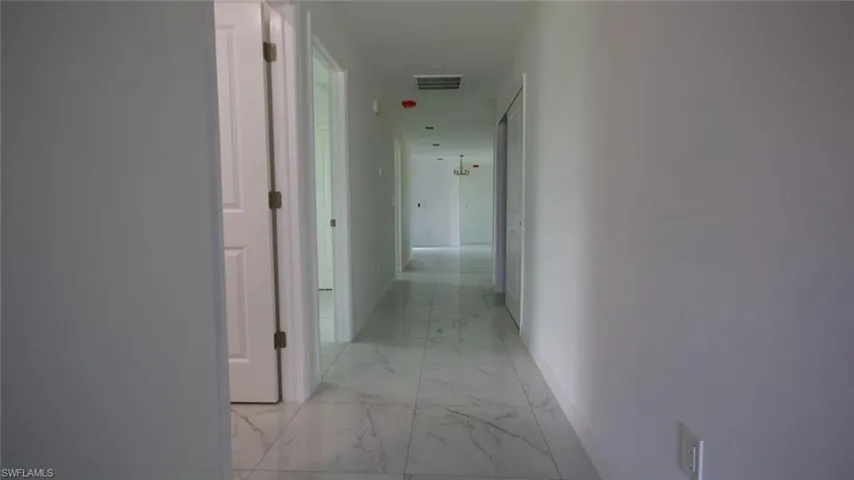 Hallway with sleek white walls and marble-patterned tile flooring
