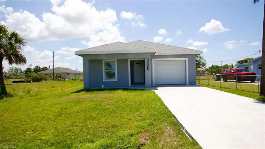 Single-story residence featuring a light gray exterior, white trim windows, a gray shingle roof, an attached garage, and a concrete driveway
