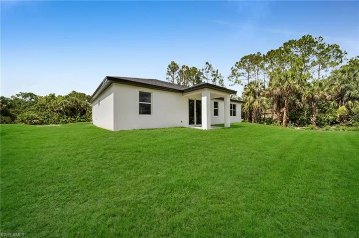 Back of property with a yard and stucco siding