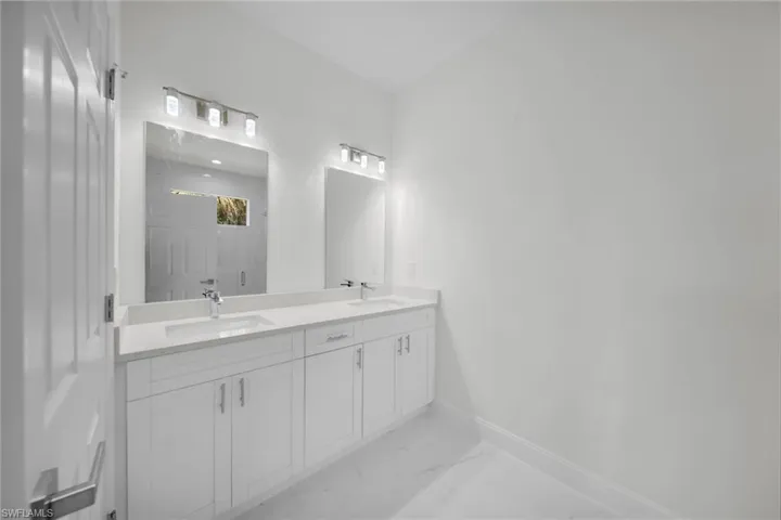 Bathroom with double vanity, marble finish floors, and a marble finish shower