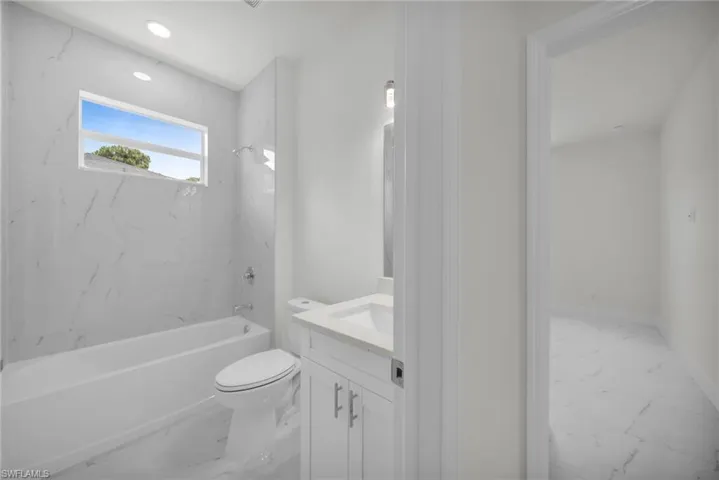 Full bathroom with marble finish flooring, vanity, and shower / washtub combination