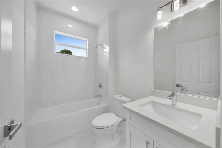 Bathroom featuring vanity, shower / bathtub combination, and marble look tiles