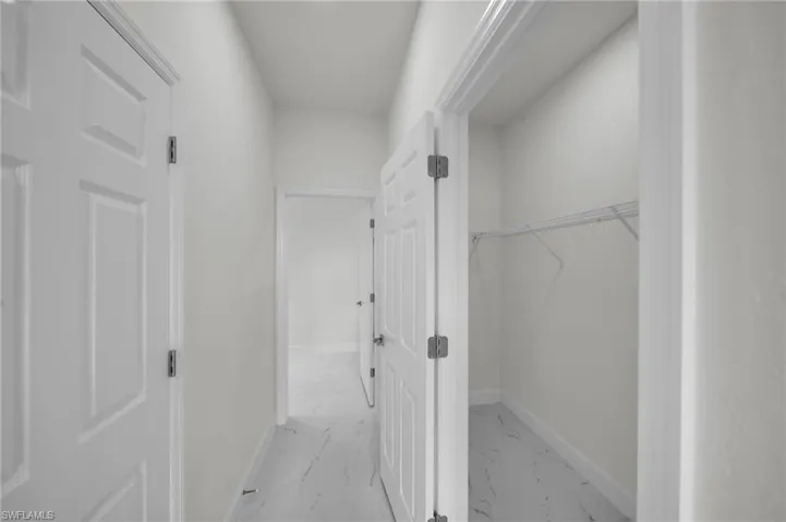 Hallway featuring light marble finish flooring and baseboards