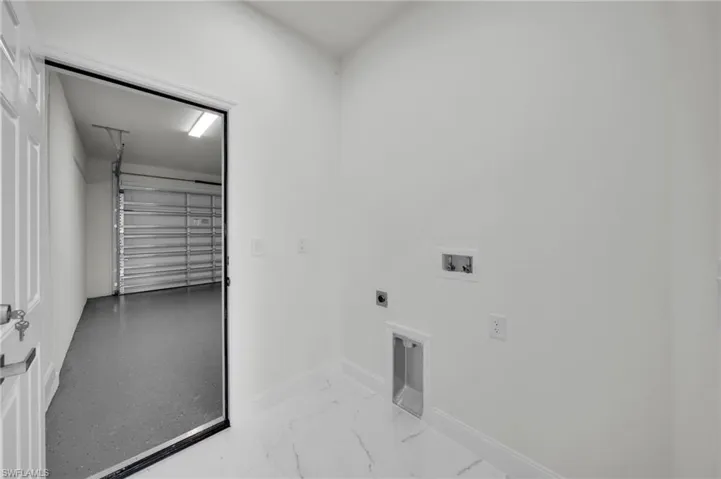 Laundry room with hookup for an electric dryer, hookup for a washing machine, marble finish flooring, and a garage