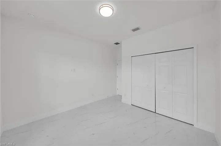 Unfurnished bedroom featuring light marble finish floors and a closet