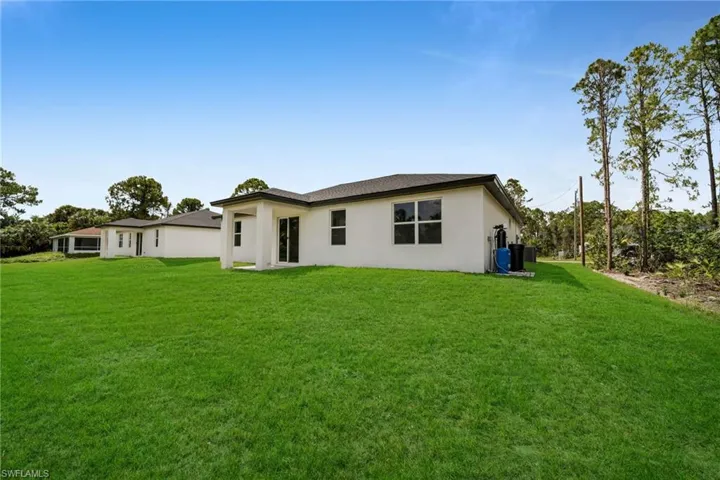Rear view of property with stucco siding and a yard