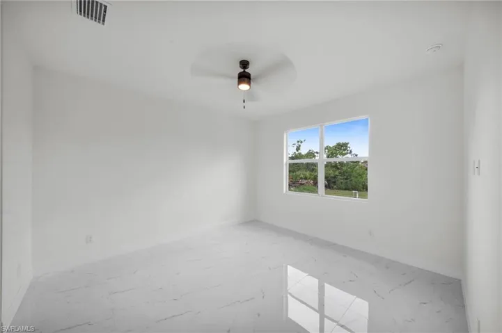 Unfurnished room featuring light marble finish flooring and a ceiling fan