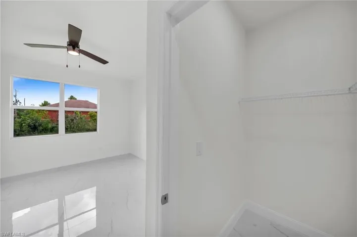 Walk in closet with marble look tile flooring and a ceiling fan