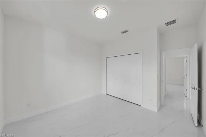 Unfurnished bedroom with light marble finish floors and a closet
