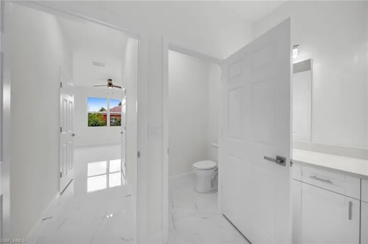 Bathroom featuring marble look tile flooring, vanity, and ceiling fan