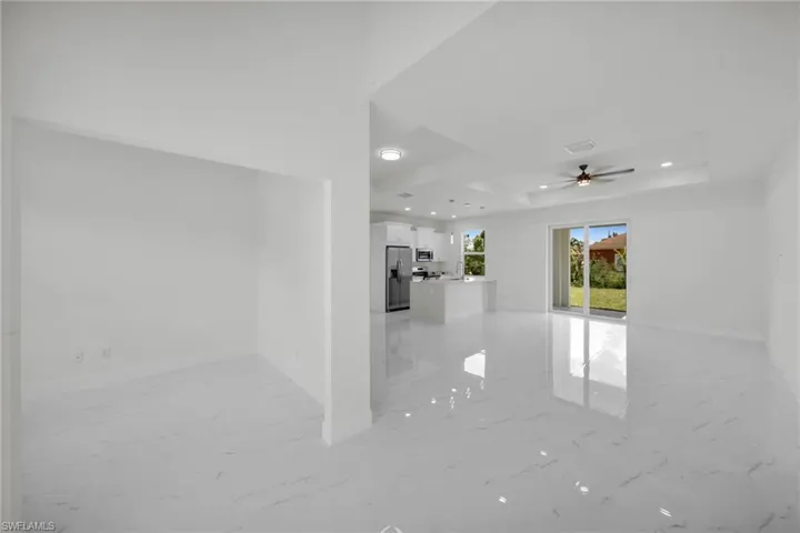 Spare room featuring light marble finish flooring, a raised ceiling, ceiling fan, and recessed lighting