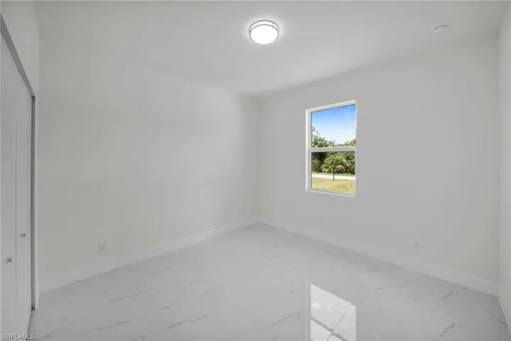 Spare room featuring light marble finish floors and a smoke detector
