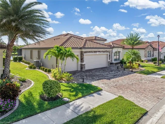 Mediterranean / spanish house with a garage, a front yard, stucco siding, decorative driveway, and stone siding